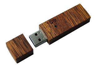 Drewniany pendrive 1GB z odłączoną zatyczką, leżący na białym tle.